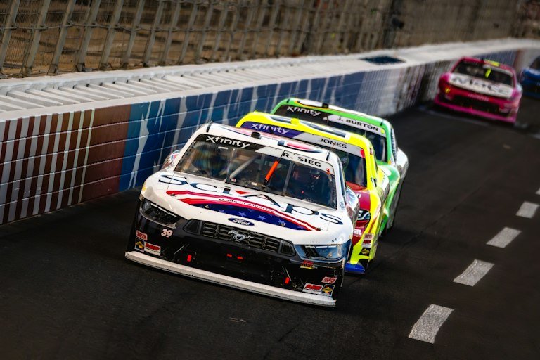 Stock cars with custom racing graphics banking a turn on track