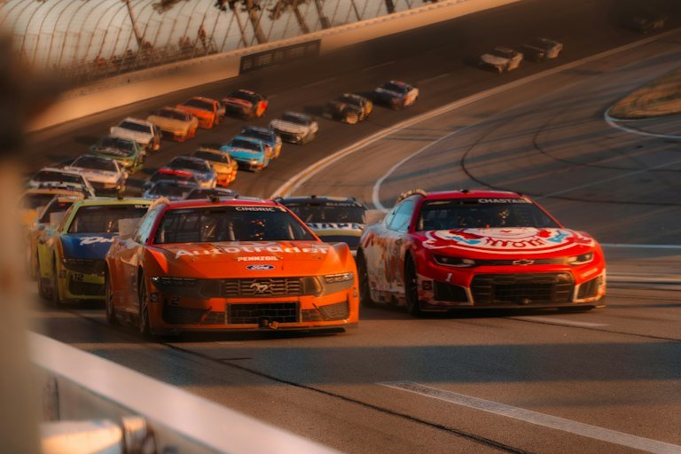 Multiple race cars with sponsor decals competing at Daytona-style event