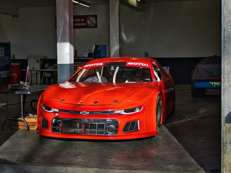 Bright red stock car graphics package finished in a Daytona Beach race shop garage